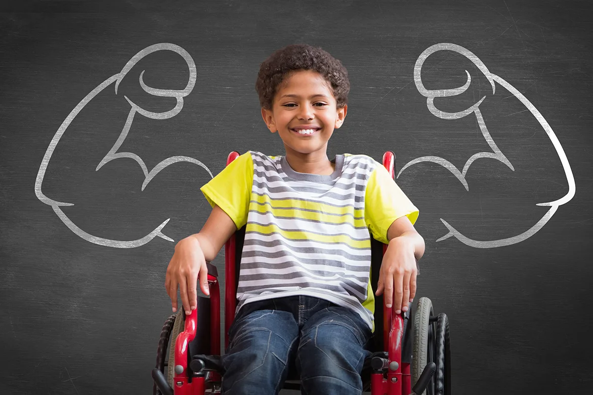 Image of a child in a wheelchair with a drawing of boxers arms on black board
